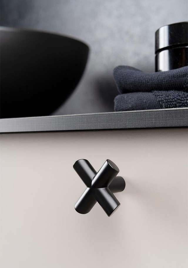 EQUIS kreuzförmiger Zamakknopf im Industrial-Design an einer modernen Möbeltür montiert.